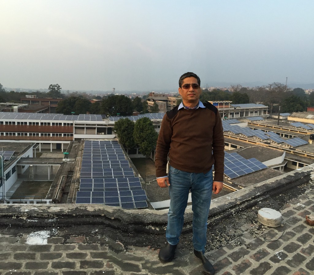 Kunwer Sachdev on a rooftop overlooking Su-Kam solar arrays across PEC Chandigarh campus buildings
