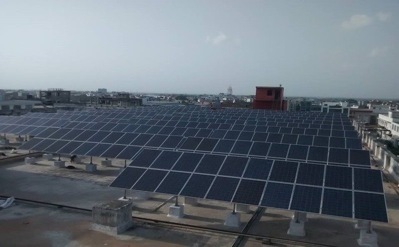 Rani Polymers Manesar — Su-Kam rooftop solar array on concrete footings overlooking industrial belt