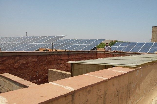 Rooftop solar panel rows on State Bank Academy building with person for scale